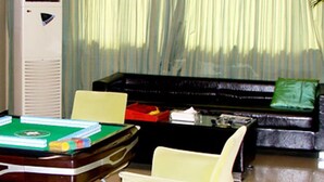 A room with a pool table, a sofa, and a television.