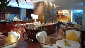 Eine Hotelhalle mit Korbstühlen, einer Rezeption und einem Barbereich.