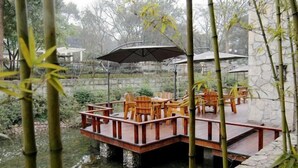 Eine Holzterrasse über dem Wasser mit Stühlen und einem Sonnenschirm.
