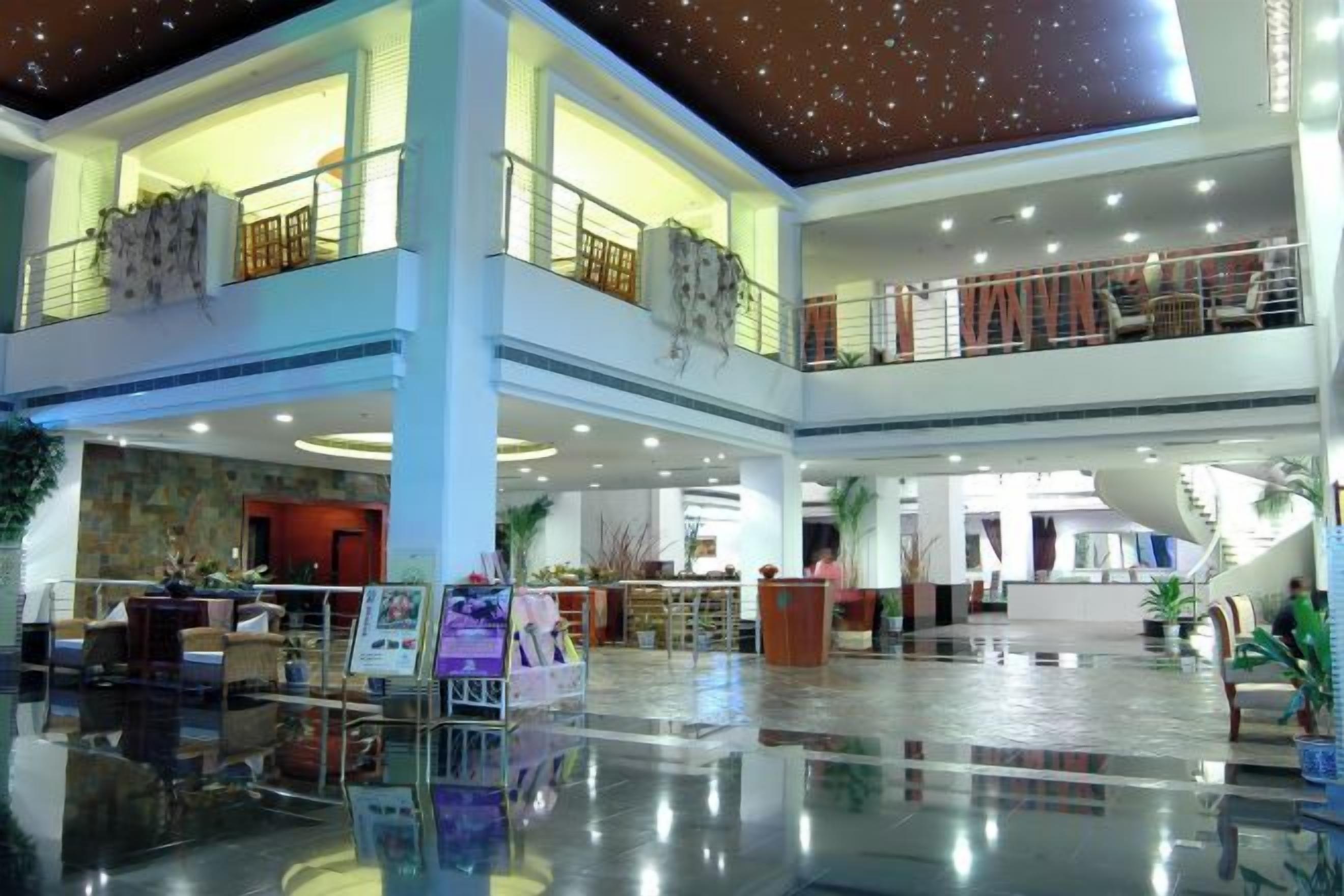 A multi-level hotel lobby with a central atrium, seating areas, and a staircase.