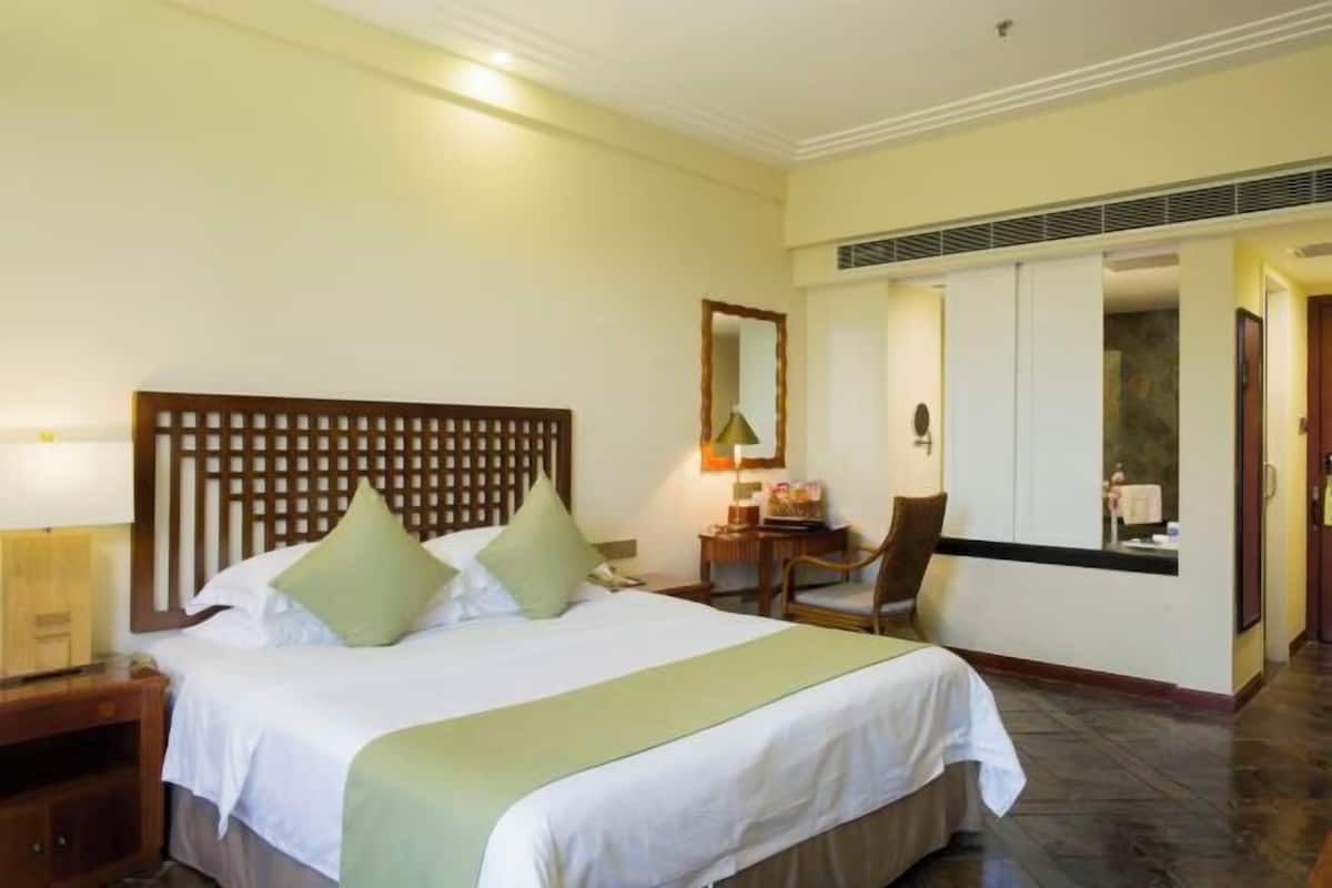 Una habitación de hotel con una cama grande, un escritorio, una silla y un espejo.