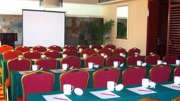 A conference room with multiple tables and chairs, equipped with nameplates, cups, and notepads.