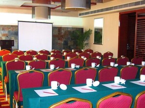 A conference room with multiple tables and chairs, equipped with nameplates, cups, and notepads.