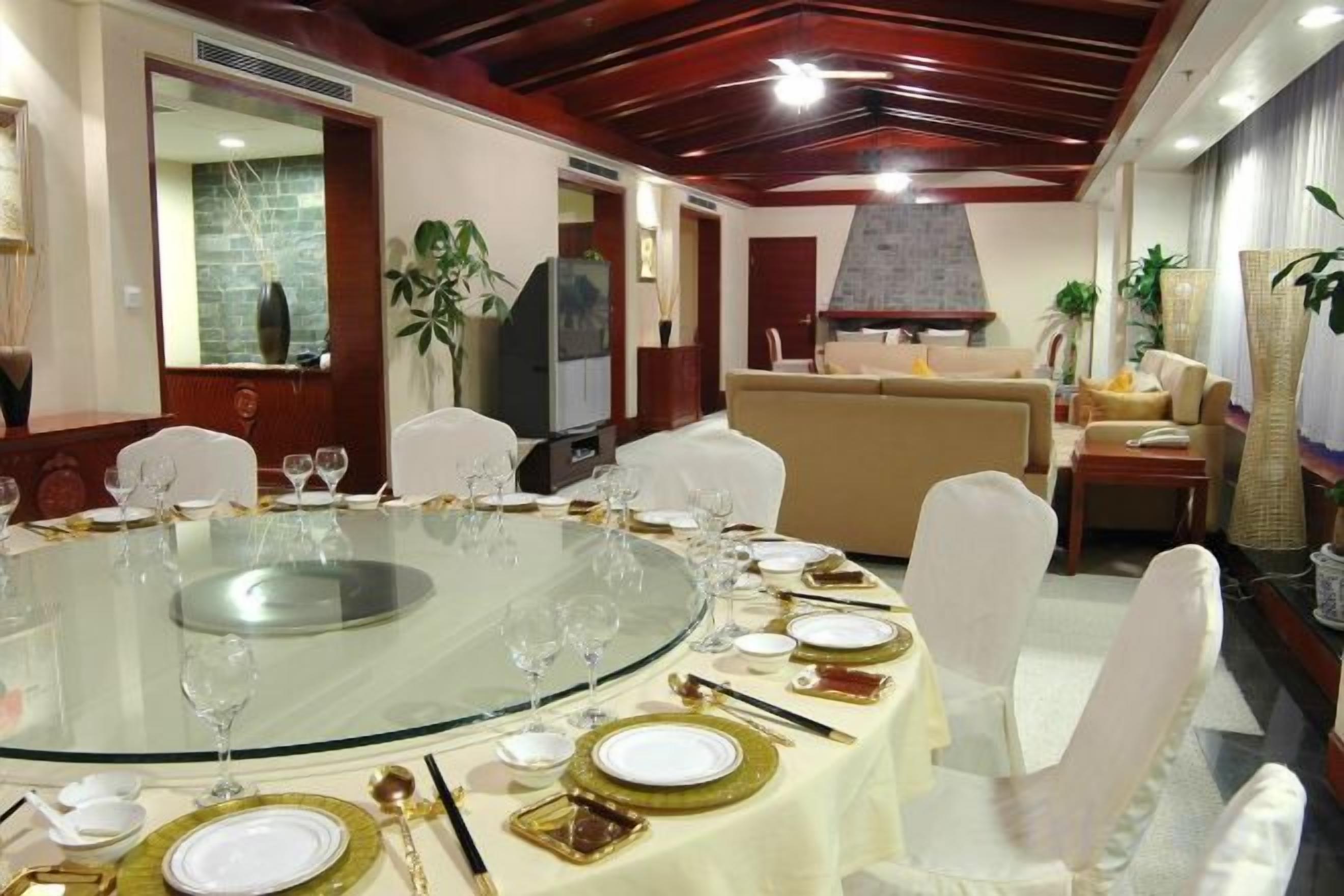 A dining area with a round glass table set for a meal, surrounded by white chairs.