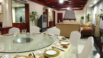 A dining area with a round glass table set for a meal, surrounded by white chairs.