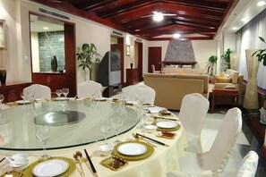 A dining area with a round glass table set for a meal, surrounded by white chairs.