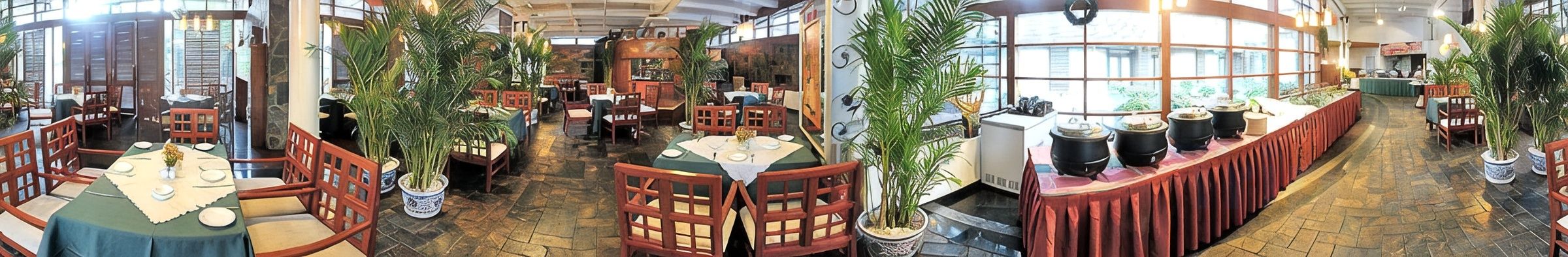 A spacious restaurant with multiple dining areas, wooden furniture, and potted plants.