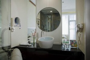A bathroom with a round mirror, a white sink, a towel, a hairdryer, and a phone on the wall. - 88 Eling Park Hotel (Chongqing Eling Erchang) (Chongqing)