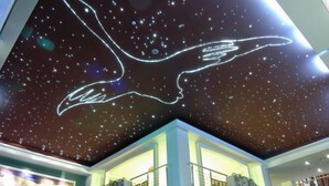 Ein modernes Gebäude mit Himmel-Design und einer großen, beleuchteten Handgrafik.