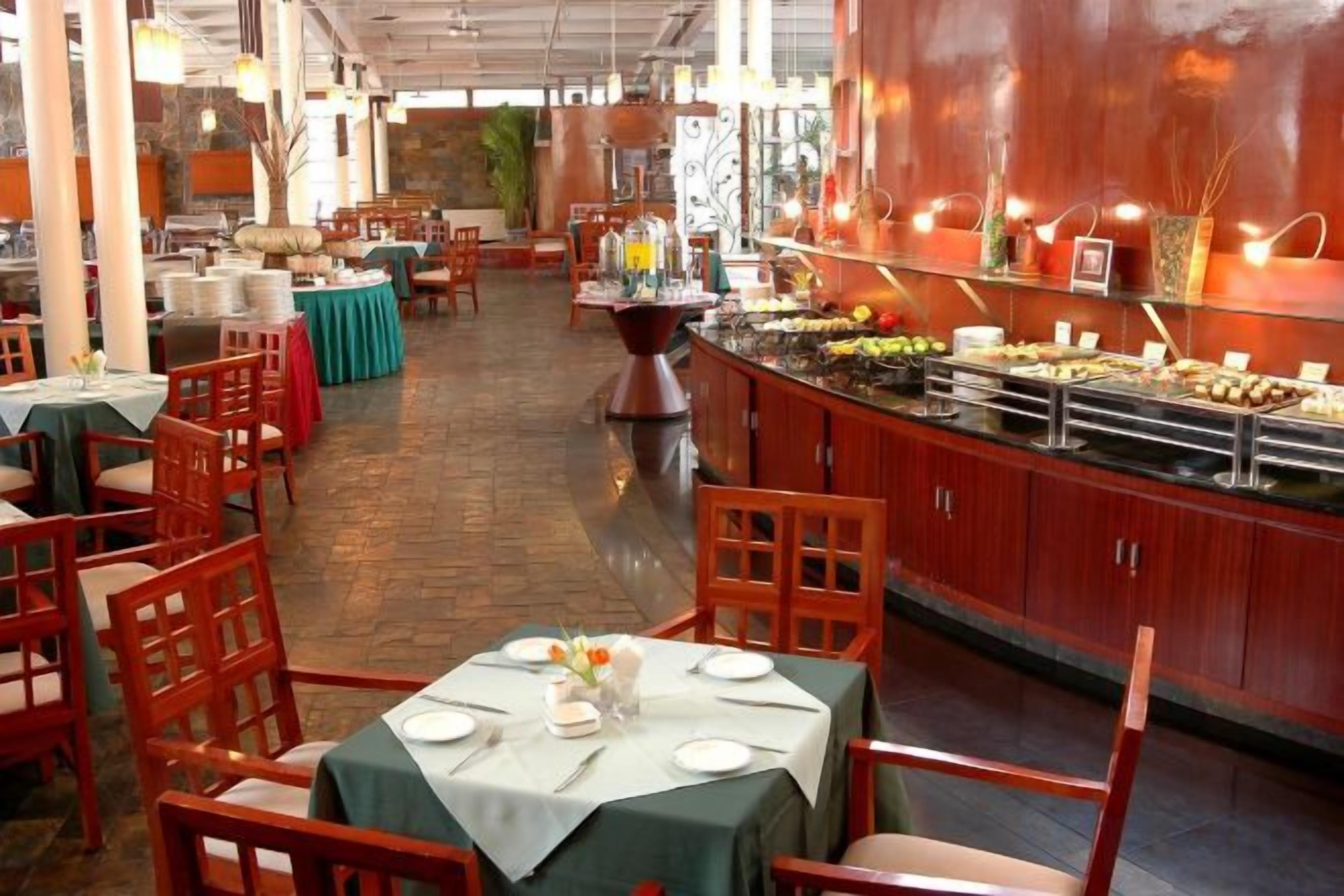 Un restaurante con bufé, sillas y mesas de madera dispuestas para comer.