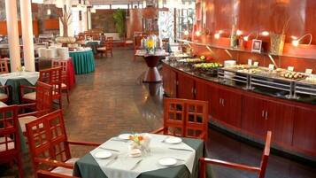 Un restaurante con bufé, sillas y mesas de madera dispuestas para comer.