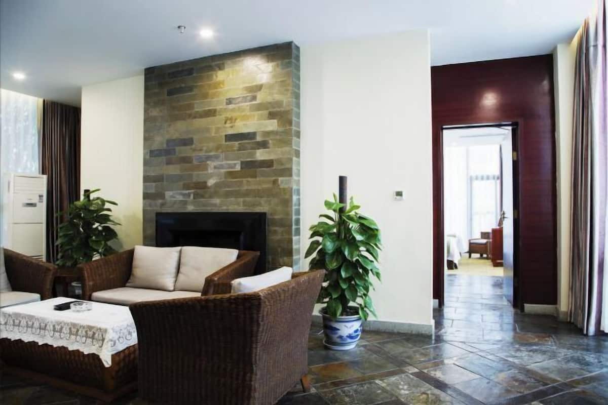 Una sala de estar moderna con chimenea de piedra, muebles de mimbre y plantas en macetas.