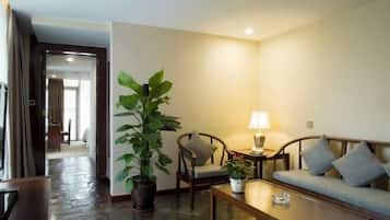 Una habitación de hotel con sofá, sillas, una mesa de centro, lámpara y planta en maceta.