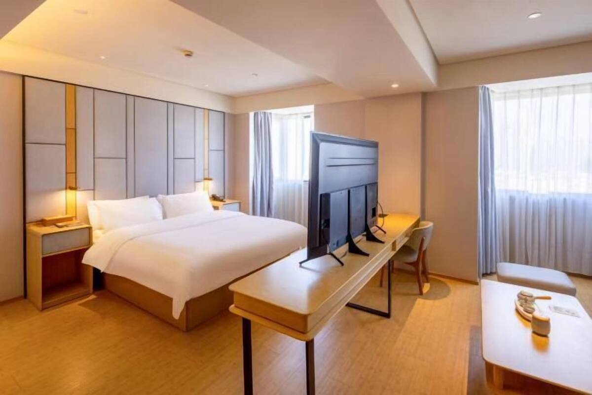 A hotel room with a bed, a TV, a desk, and a chair.