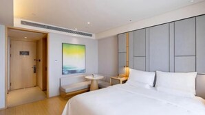 A modern hotel room with a large bed, a small round table, a bench, and a painting on the wall. - JI Hotel (Baizhang East Road Ningbo) (Ningbo)