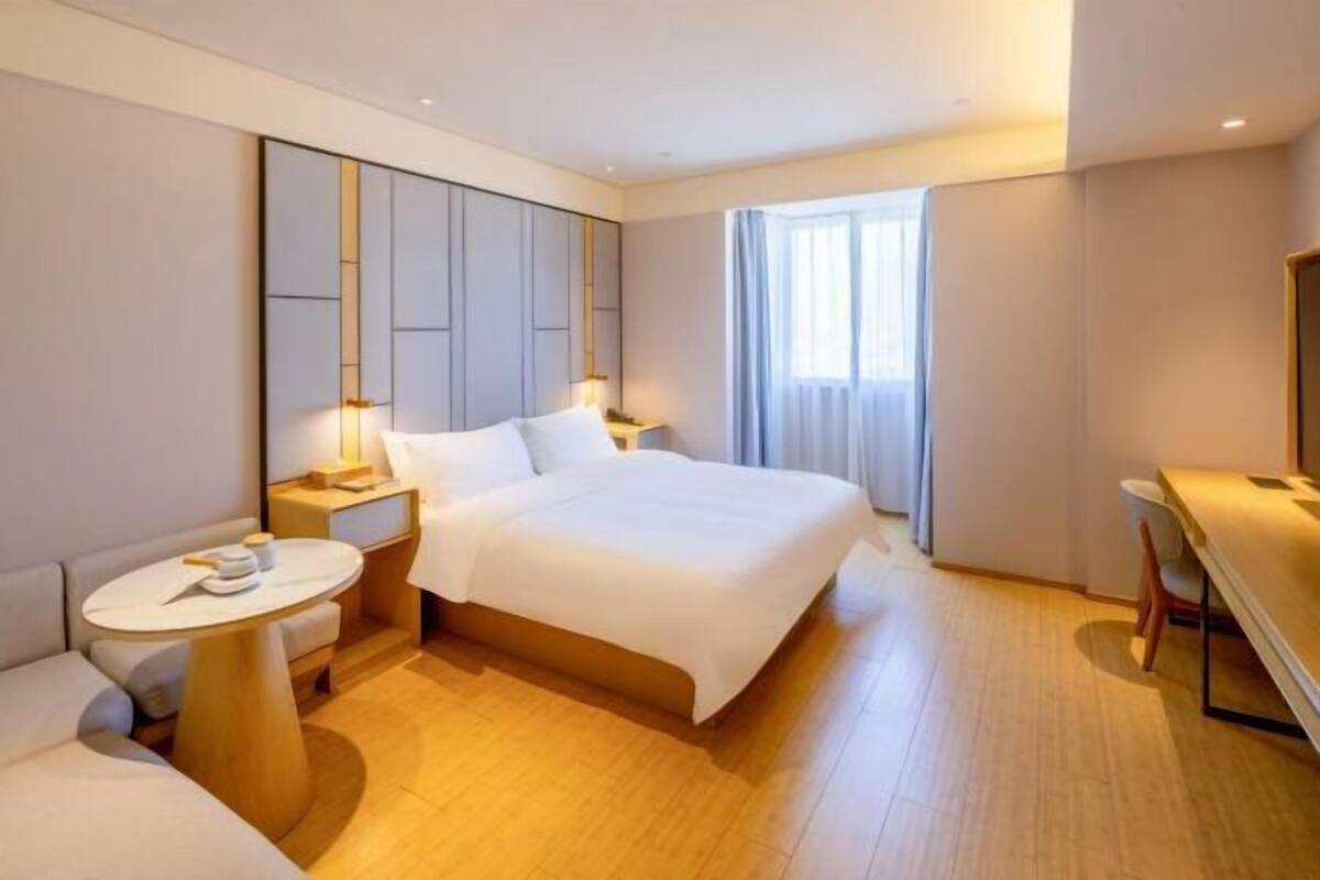 A hotel room with a bed, bedside tables, a desk, and a chair.
