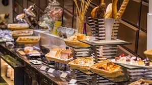 Een buffet met diverse gerechten, waaronder brood, gebak en desserts.