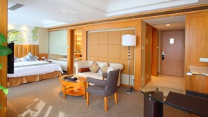 A hotel room with a bed, a sofa, a small round table, and a desk. - Jinling Plaza Changzhou (Changzhou)