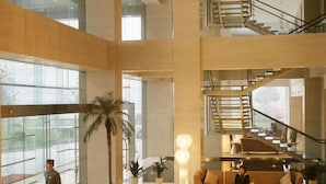 A spacious lobby with a high ceiling, a staircase, and a seating area. - Jinling Plaza Changzhou (Changzhou)