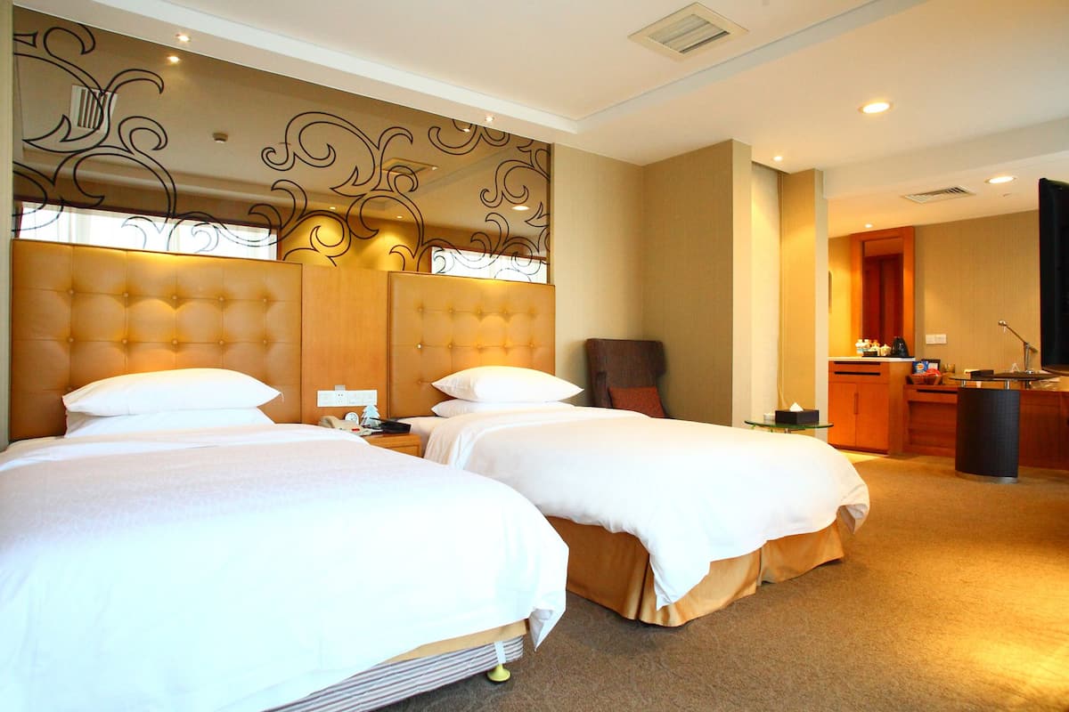 Une chambre d’hôtel avec deux lits, un petit bureau et une kitchenette.