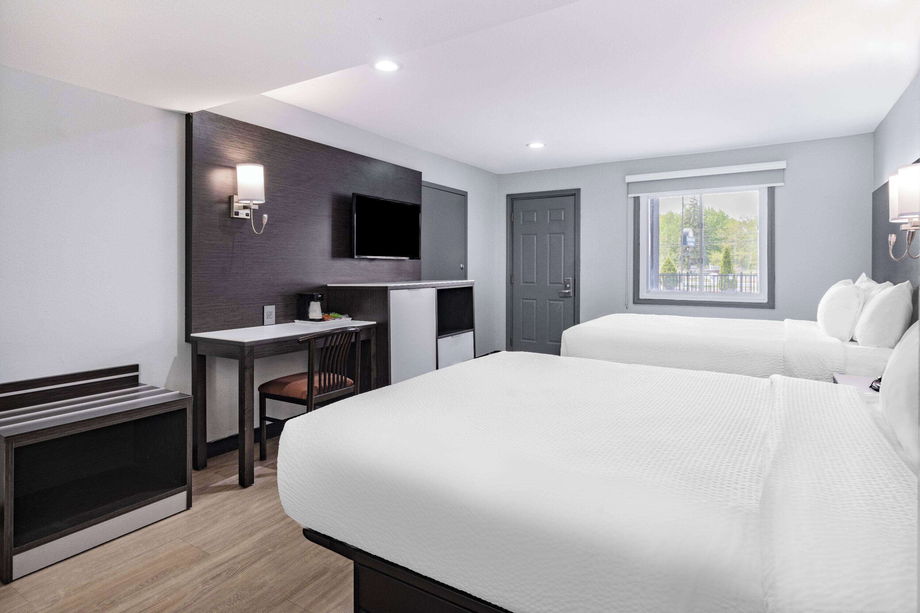 Una moderna camera d'albergo con un letto, una scrivania, un televisore e una finestra con vista.