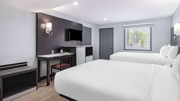 Una moderna camera d'albergo con un letto, una scrivania, un televisore e una finestra con vista.