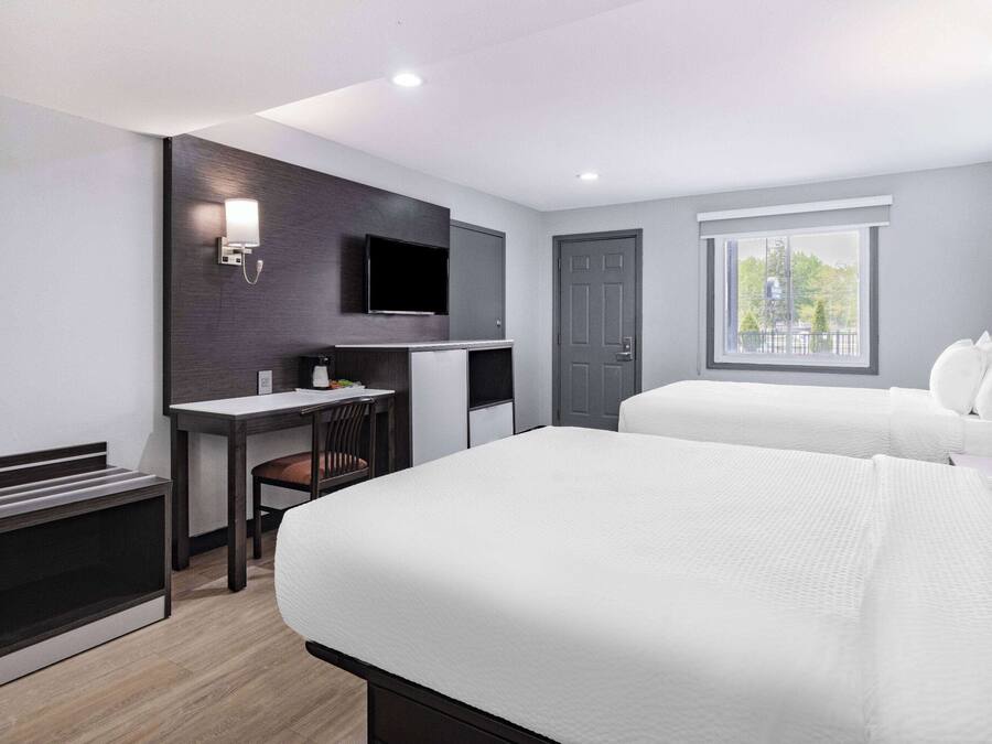 Una moderna camera d'albergo con un letto, una scrivania, un televisore e una finestra con vista.