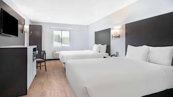 Quarto de hotel com duas camas, televisão, escrivaninha e uma cadeira.