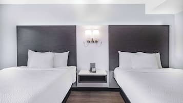 Una camera d'albergo con due letti, un comodino con un telefono e un tavolino, e un lampadario fissato al muro.