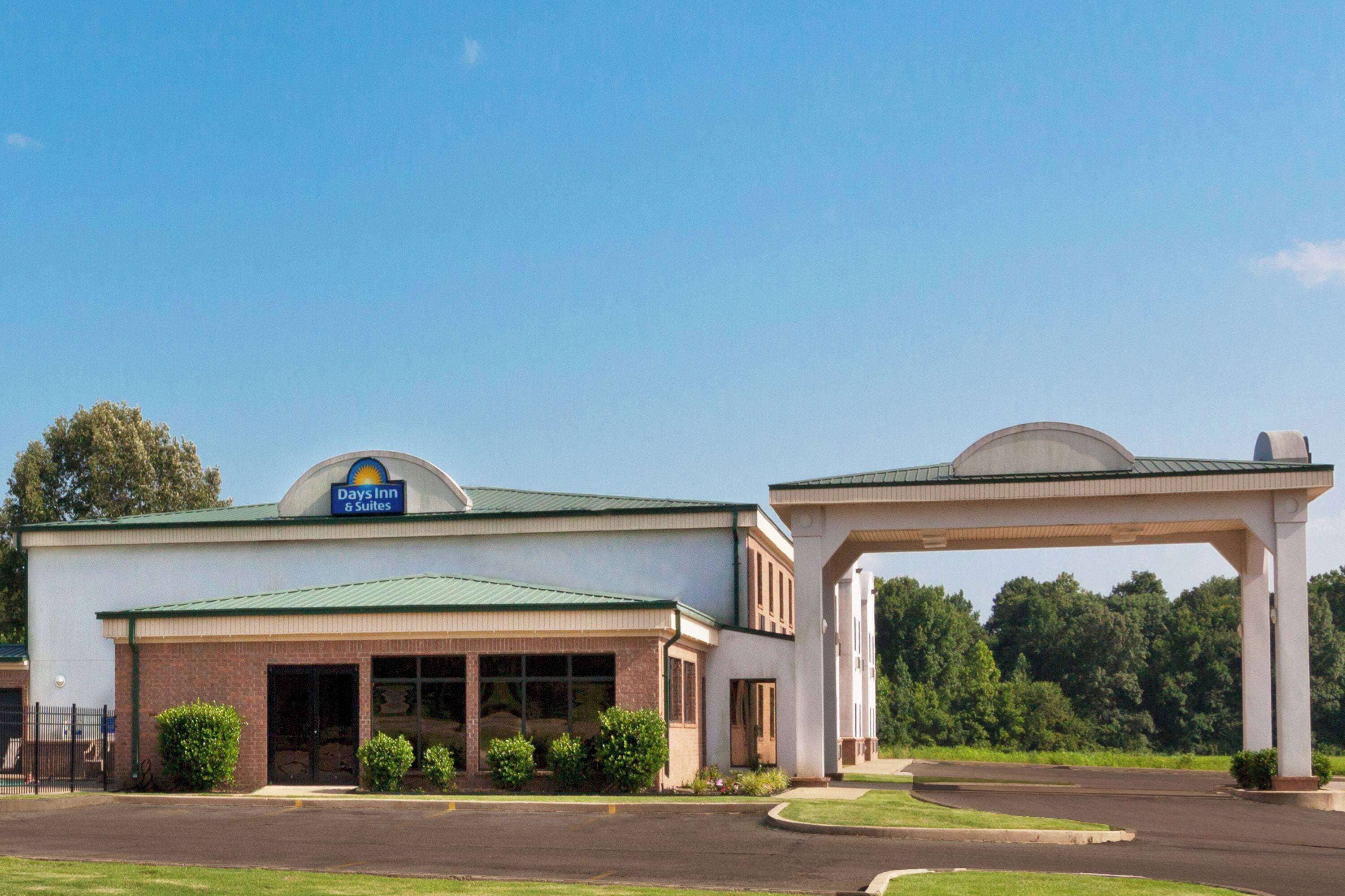 A Days Inn & Suites building with a green roof, a covered entrance, and a parking lot.