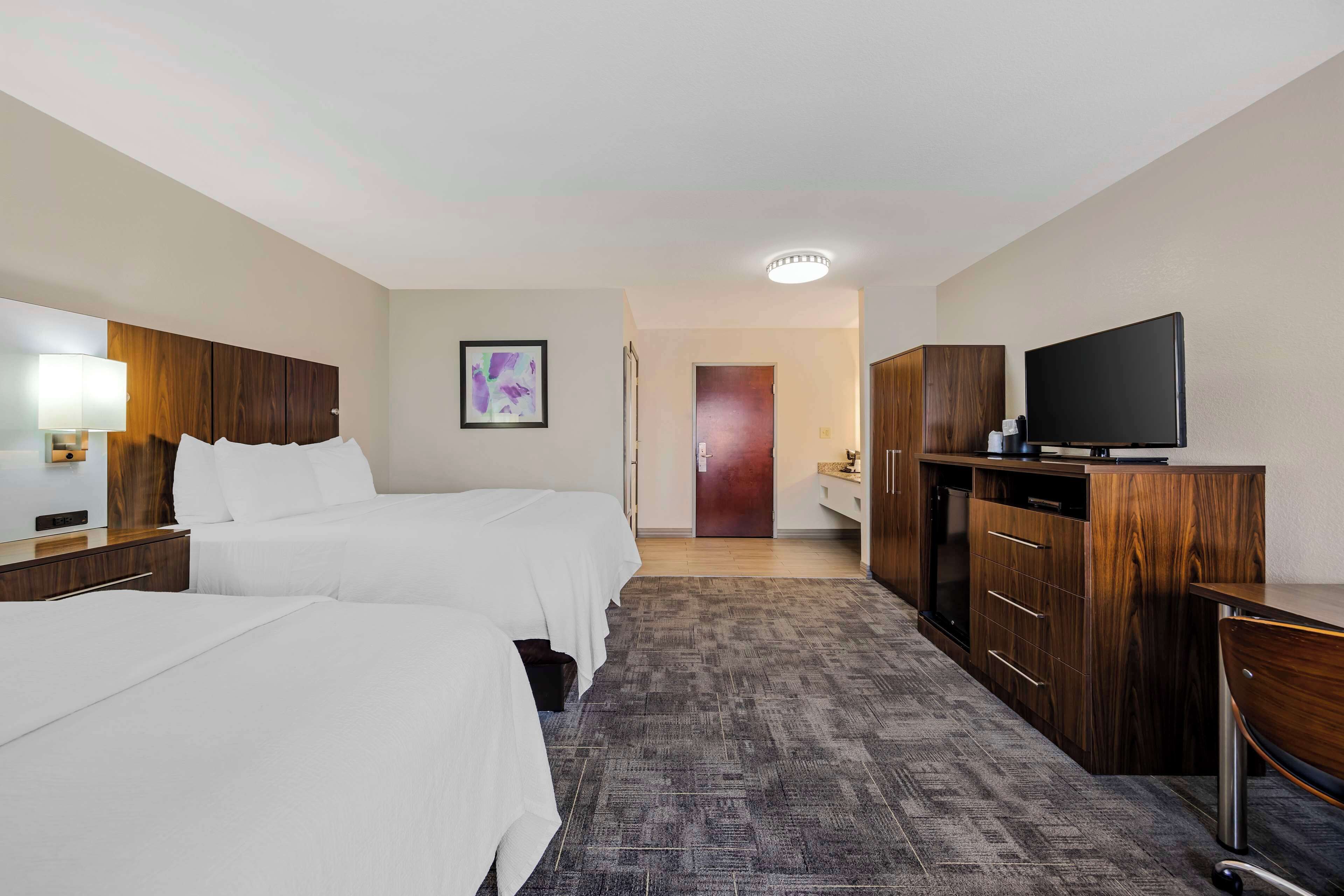A hotel room with two beds, a TV, a desk, and a wardrobe.