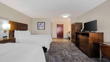 A hotel room with two beds, a TV, a desk, and a wardrobe.