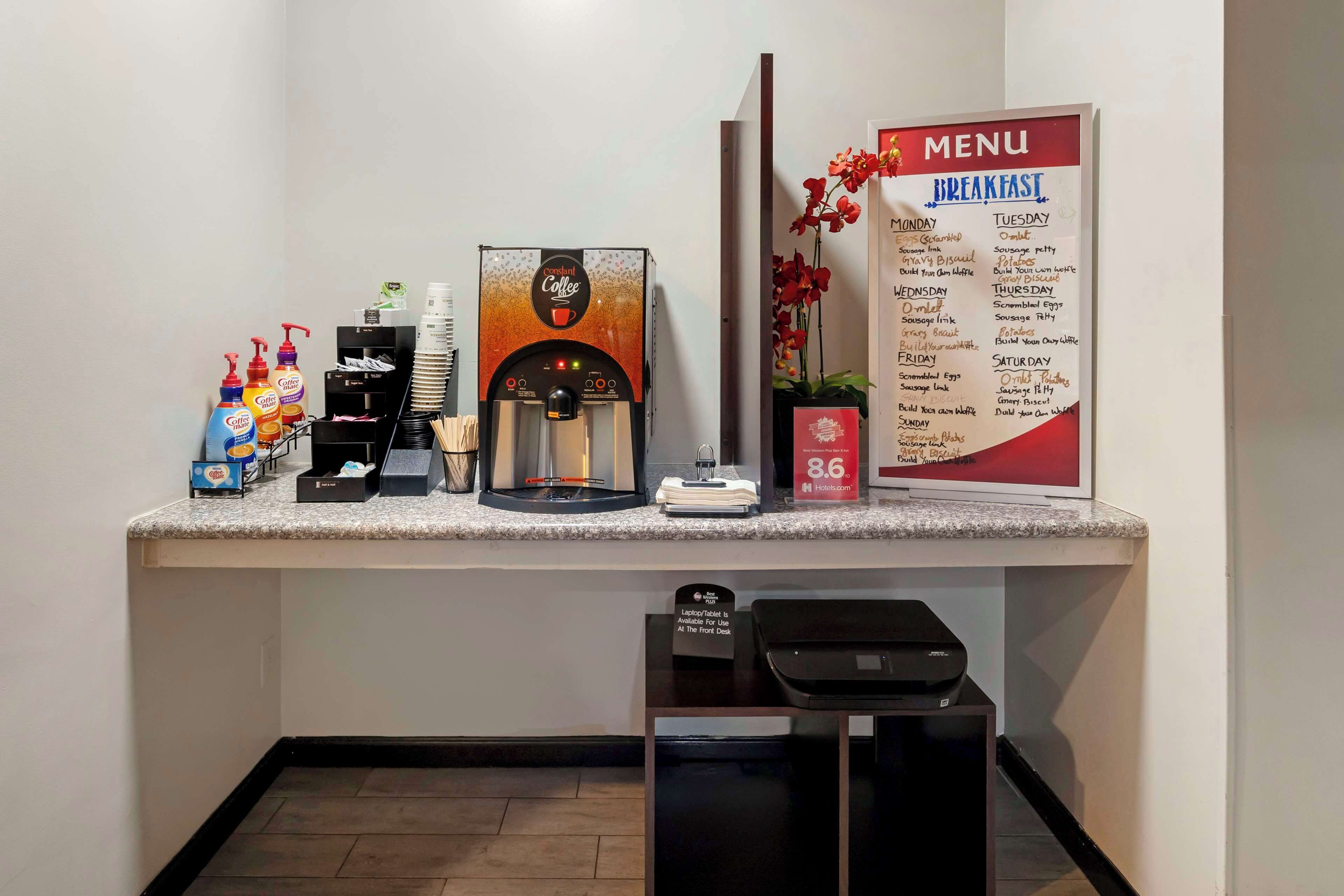 Un espace dédié au café, équipé d’une machine à café, de distributeurs de condiments et d’un panneau affichant les différentes options proposées pour le petit-déjeuner.