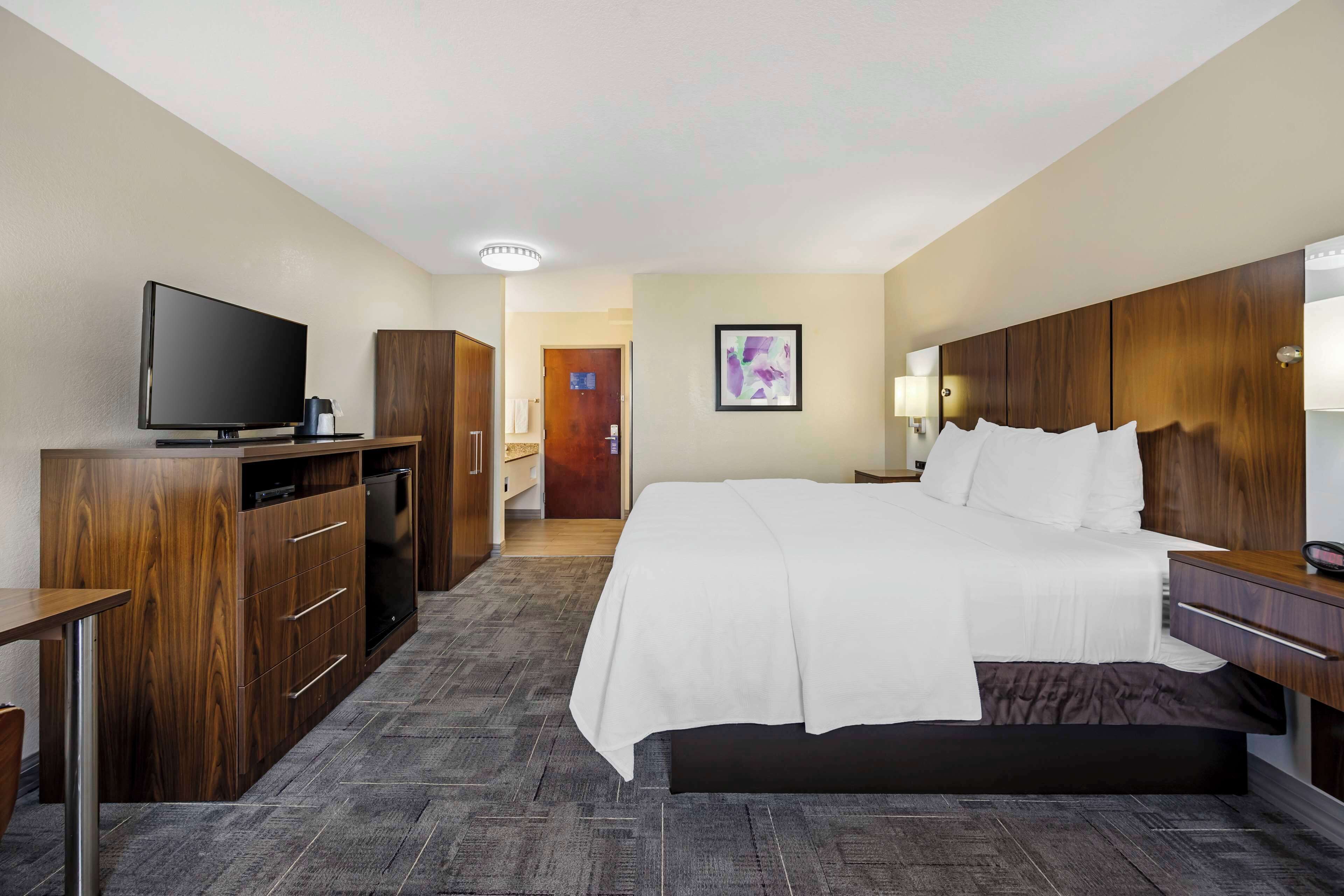 Een hotelkamer met een groot bed, een televisie, houten meubels en een vloerbedekking.