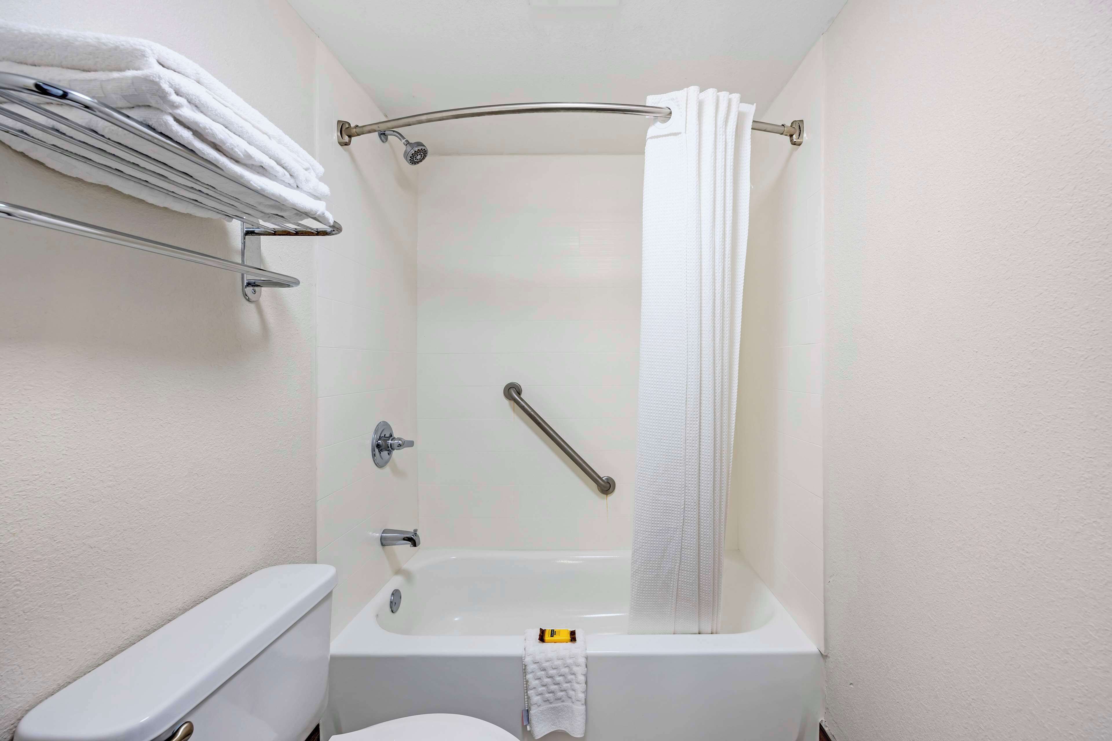 Un baño pequeño con bañera, inodoro y toallero.