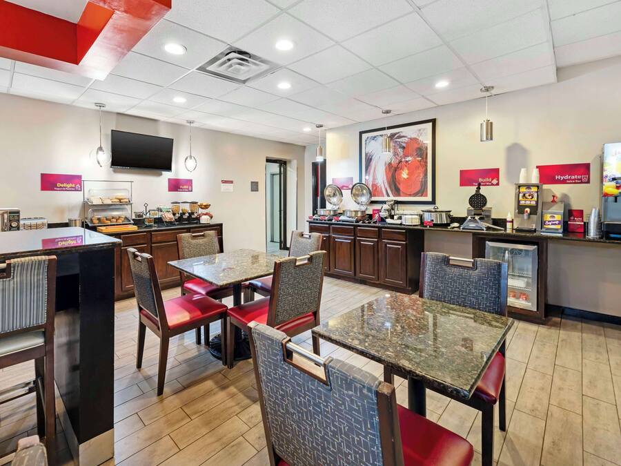 A modern restaurant with a counter, seating area, and kitchen.