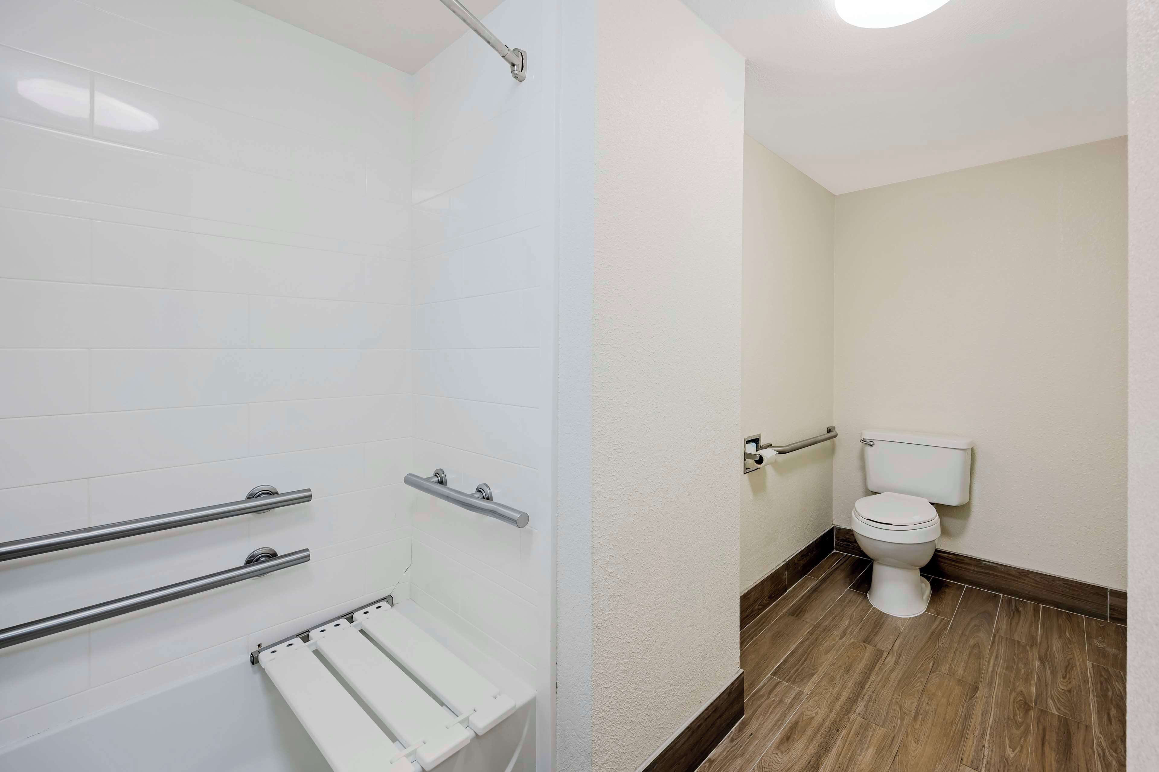 Une salle de bain équipée d’une douche, de toilettes et de barres d’appui.