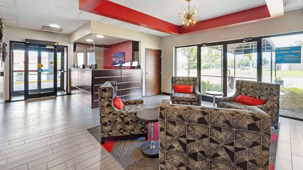A hotel lobby with a reception desk, patterned sofas, and a large window offering a view outside. - Best Western Gen X Inn (Memphis)