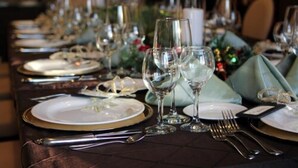A dining table set with plates, glasses, and cutlery, suggesting a formal dining arrangement.