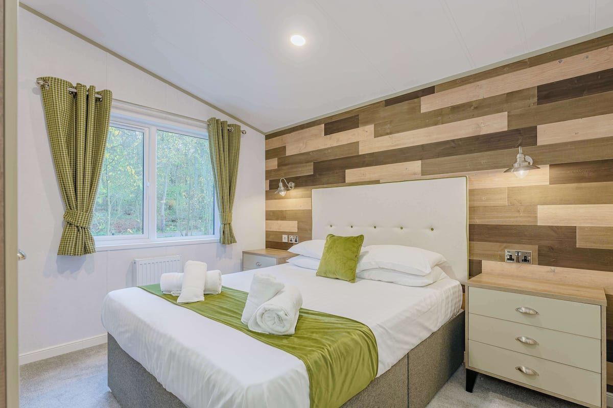 Een moderne slaapkamer met een groot bed, nachtkastjes en een raam met gordijnen.