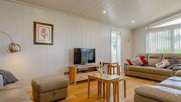 A spacious living room with a television, wooden coffee table, and two sofas.