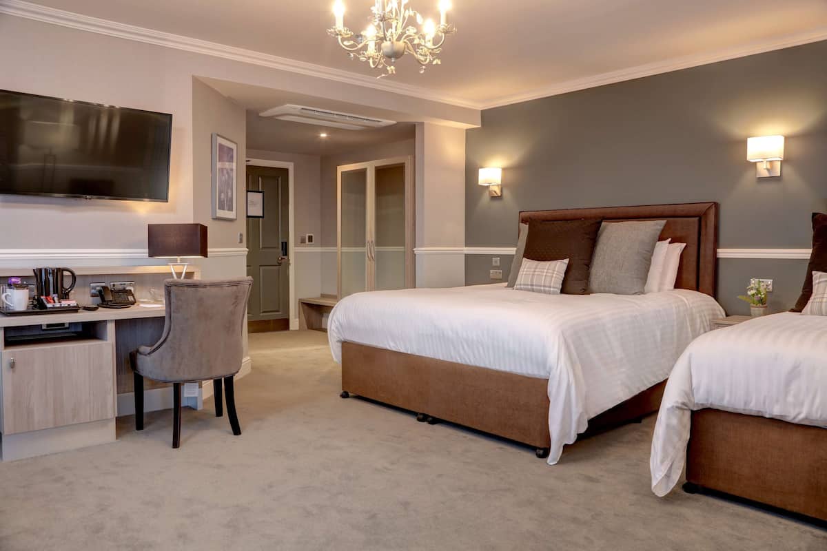 Hotelkamer met een groot bed, een bureau met stoel, een televisie en een kroonluchter.
