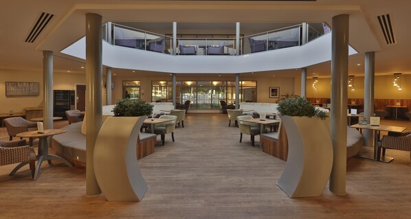 Un hall d’entrée spacieux avec un atrium central, des espaces de détente et une mezzanine.