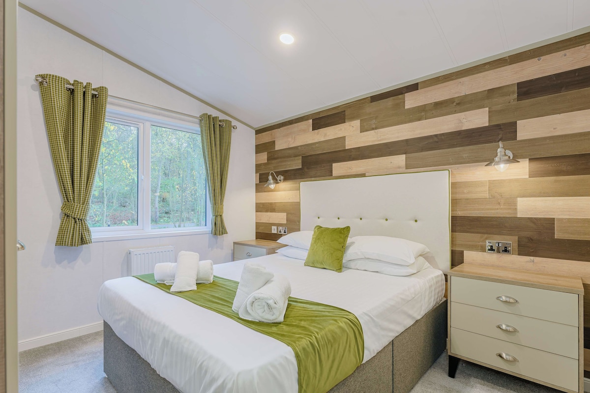 Ein modernes Schlafzimmer mit einem großen Bett, Nachttischen und einem Fenster mit Vorhängen.