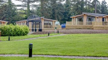 A row of wooden cabins with large windows and a gazebo in the center.
