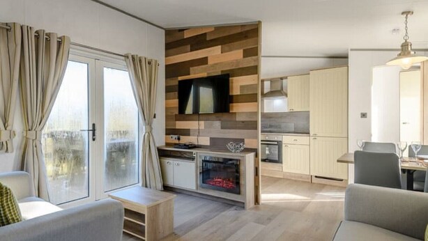 Een moderne keuken met houten details, een eetgedeelte met een tafel en stoelen, en een woonkamer met een bank en een televisie.