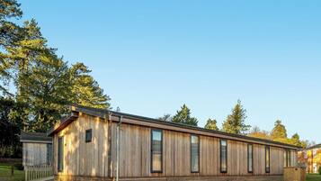 A long, single-story wooden building with large windows and a covered porch area.