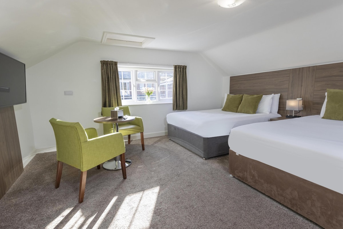 Een hotelkamer met een bed, een bureau, een stoel en een raam met gordijnen.