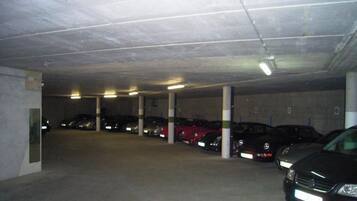 Un estacionamiento subterráneo de varios niveles con varios coches aparcados.