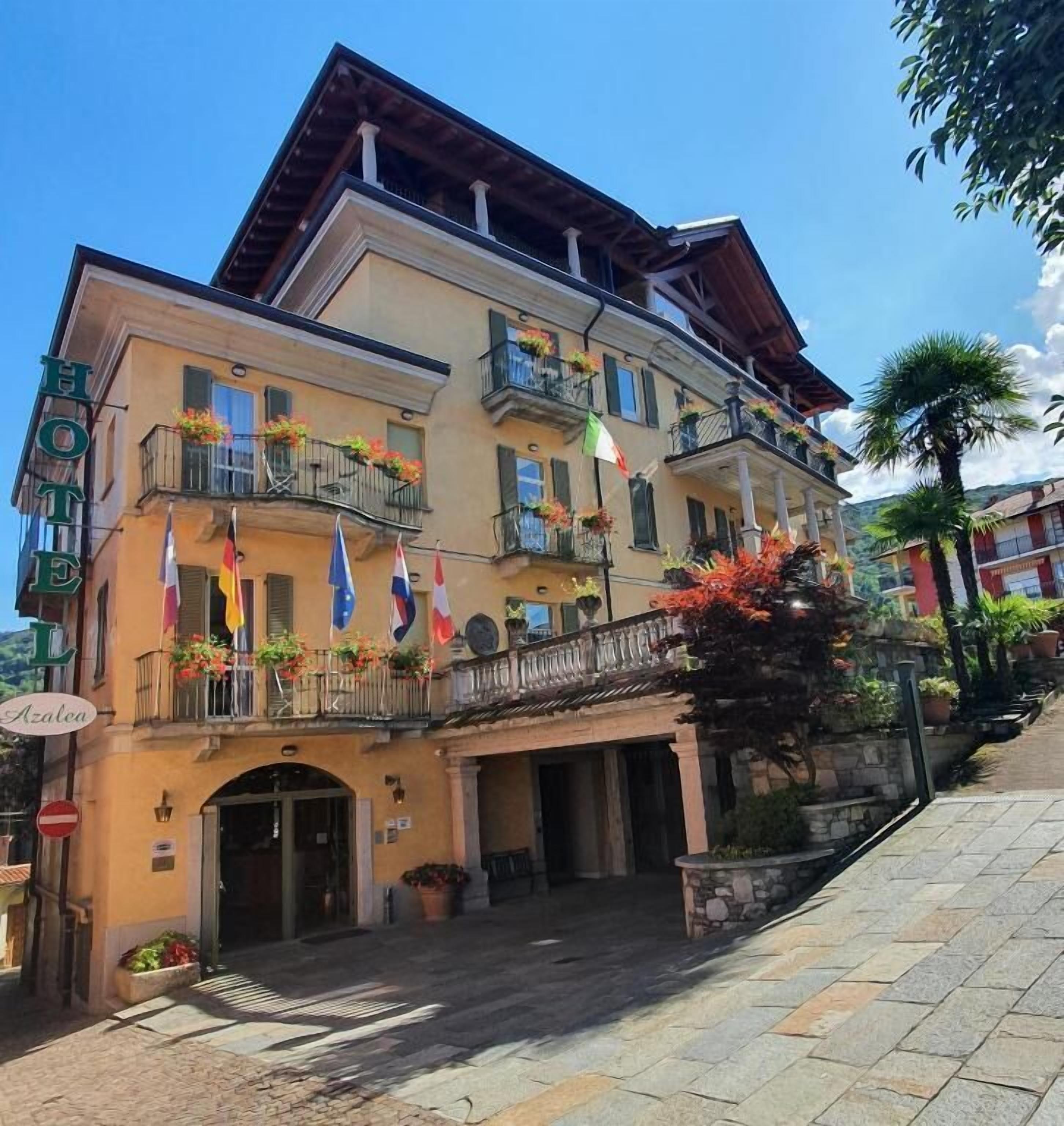 Un hotel de varios pisos con balcones, entrada a nivel de calle y fachada de piedra.